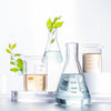 Frascos de vidrio con hojas y líquidos naturales para fórmulas ecológicas