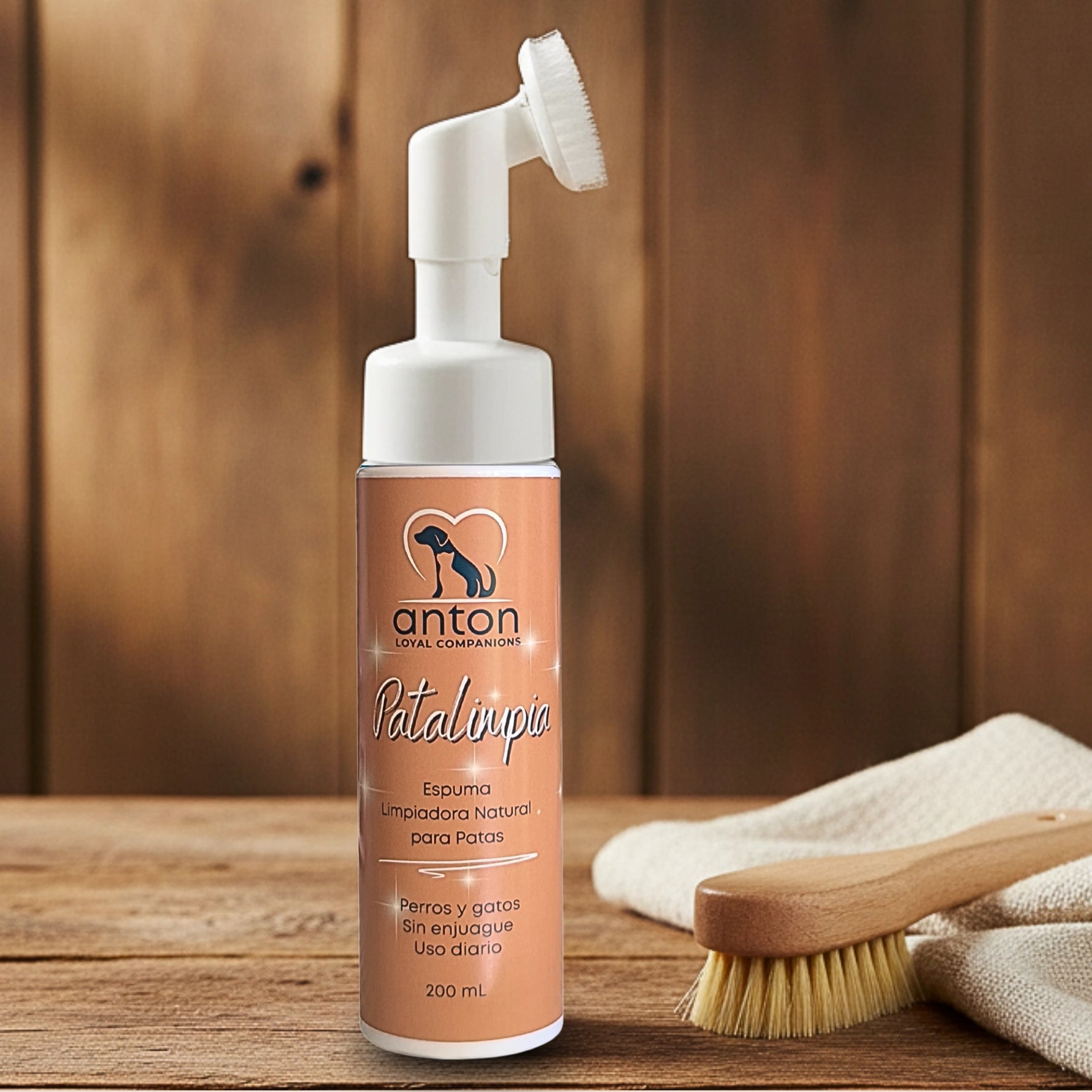 Espuma limpiadora natural para patas de perros y gatos ANTON Loyal Companions con cepillo aplicador integrado sobre fondo de madera natural
