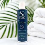 Champú natural Frescura para perros ANTON Loyal Companions sobre toallas blancas y hojas verdes, efecto antiólor y frescor duradero, uso frecuente, fórmula natural.