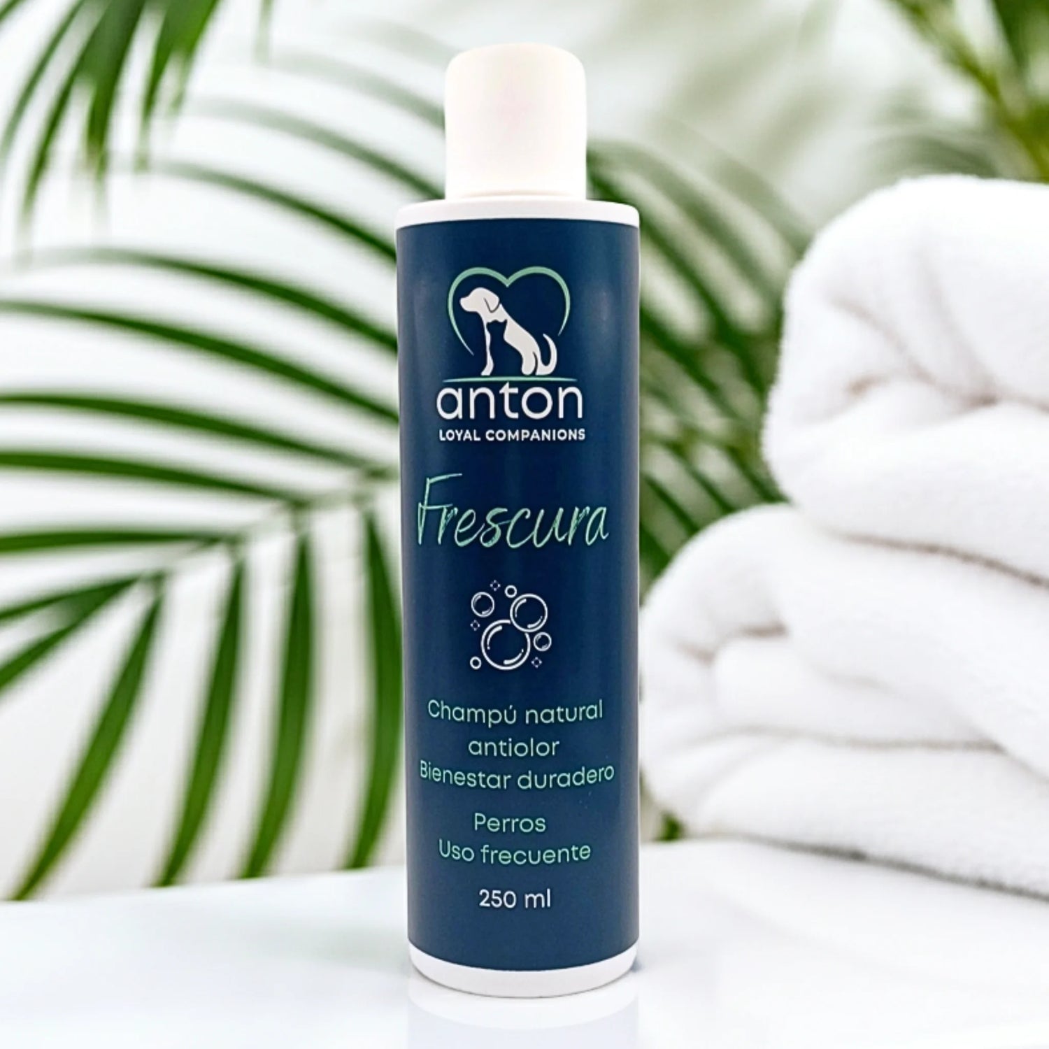 Champú natural Frescura para perros ANTON Loyal Companions sobre toallas blancas y hojas verdes, efecto antiólor y frescor duradero, uso frecuente, fórmula natural.