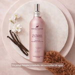 Champú seco y acondicionador Frenky Lewis Sandalwood, Jasmine & Vanilla para perros, en frasco rosa junto a flores de jazmín, vainilla y un perro de pelo rizado.