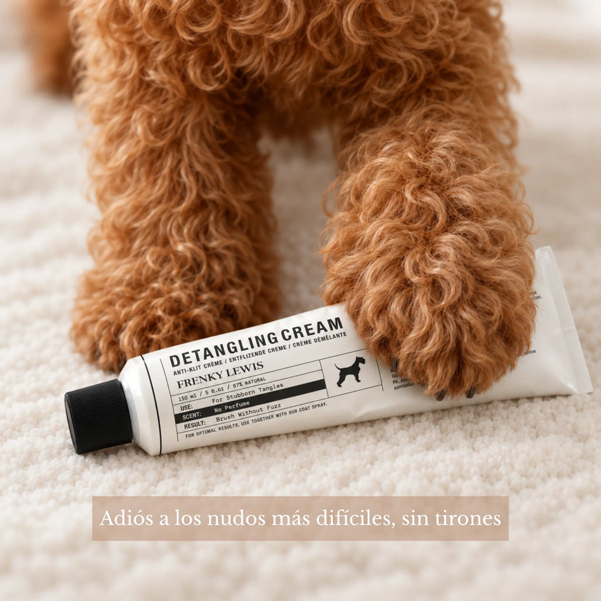 Perro de pelo rizado marrón con las patas apoyadas sobre un tubo de crema desenredante Frenky Lewis de 150 ml, para facilitar el desenredado sin tirones.