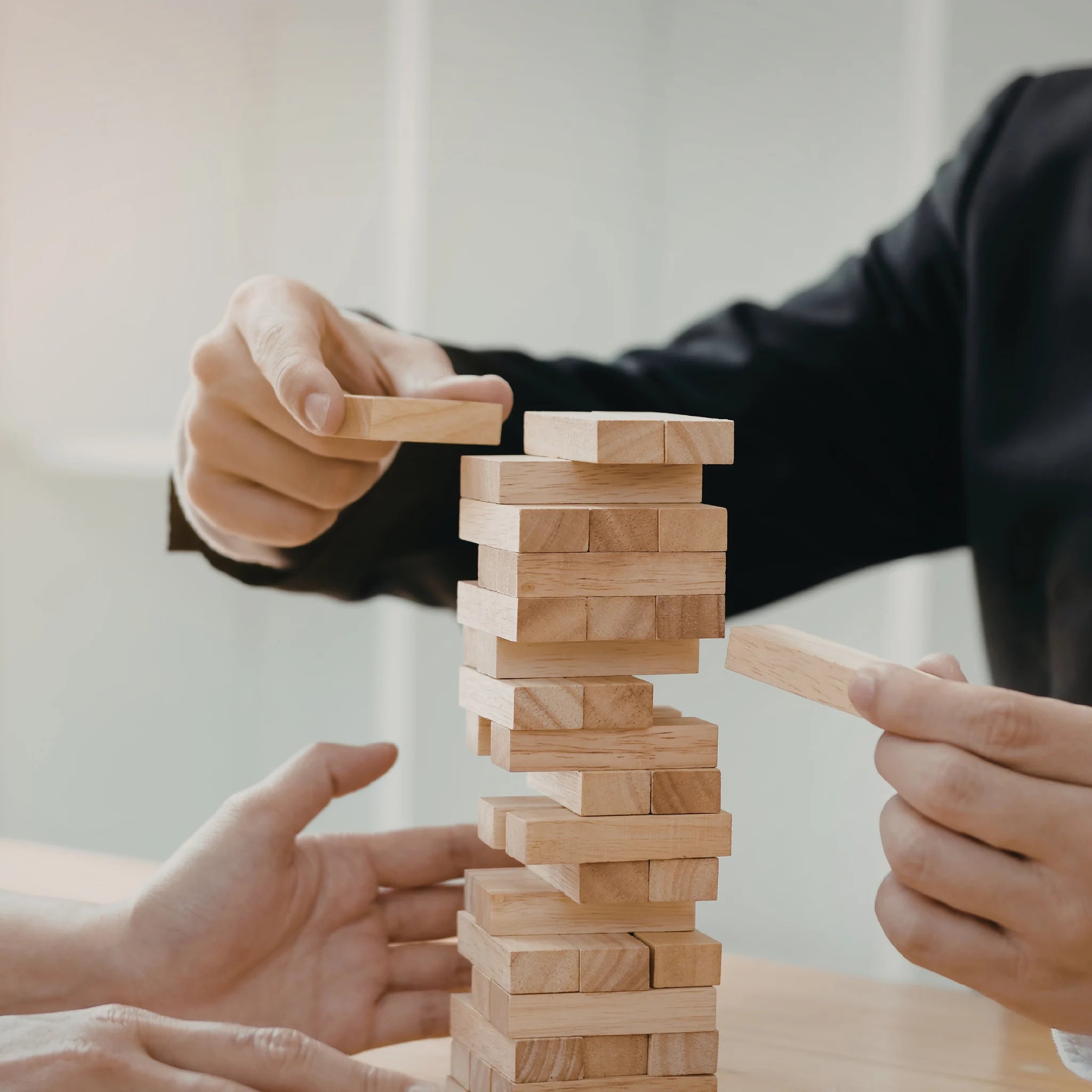 Manos construyendo una estructura de bloques que simboliza metodología y colaboración estructurada
