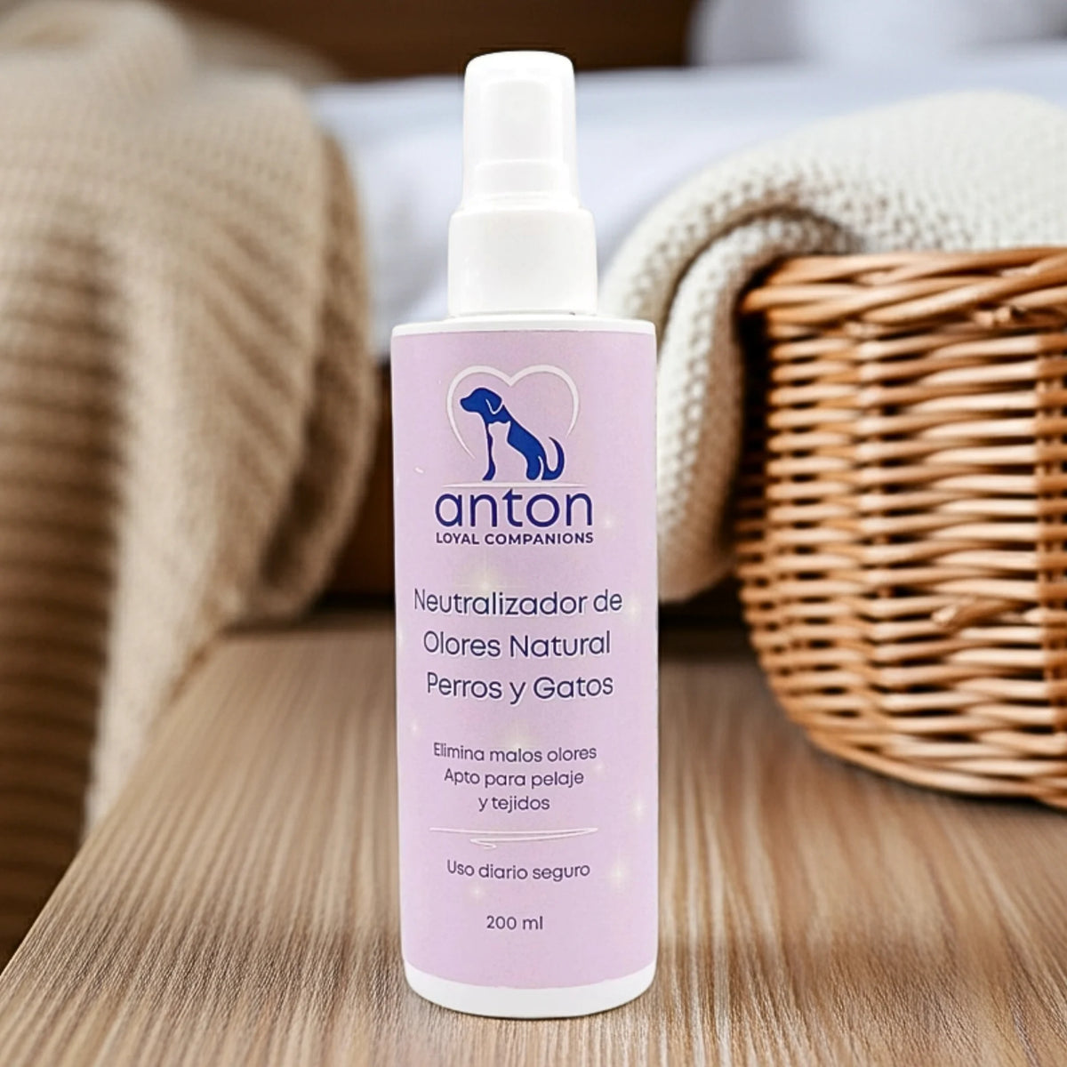 Neutralizador de olores natural para perros y gatos ANTON Loyal Companions sobre mesa con cesta y toalla, elimina malos olores del pelaje y tejidos, uso diario seguro.