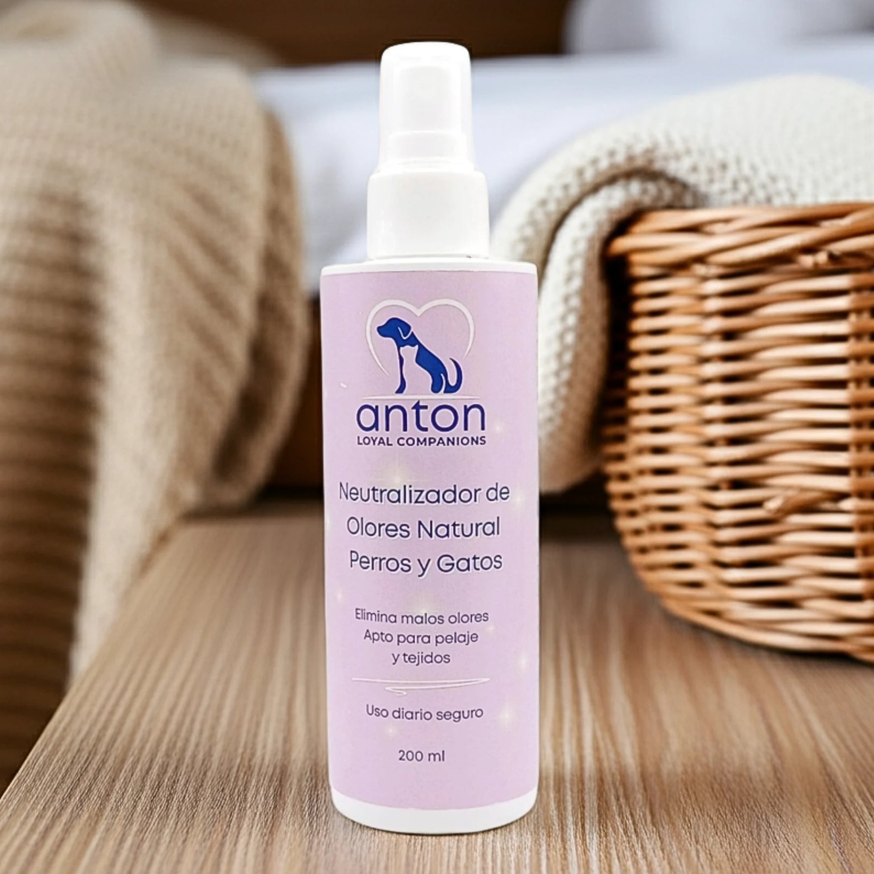 Neutralizador de olores natural para perros y gatos ANTON Loyal Companions sobre mesa con cesta y toalla, elimina malos olores del pelaje y tejidos, uso diario seguro.